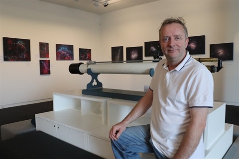 Dr Chadwick sitting beside his Southern Night Sky exhibition.